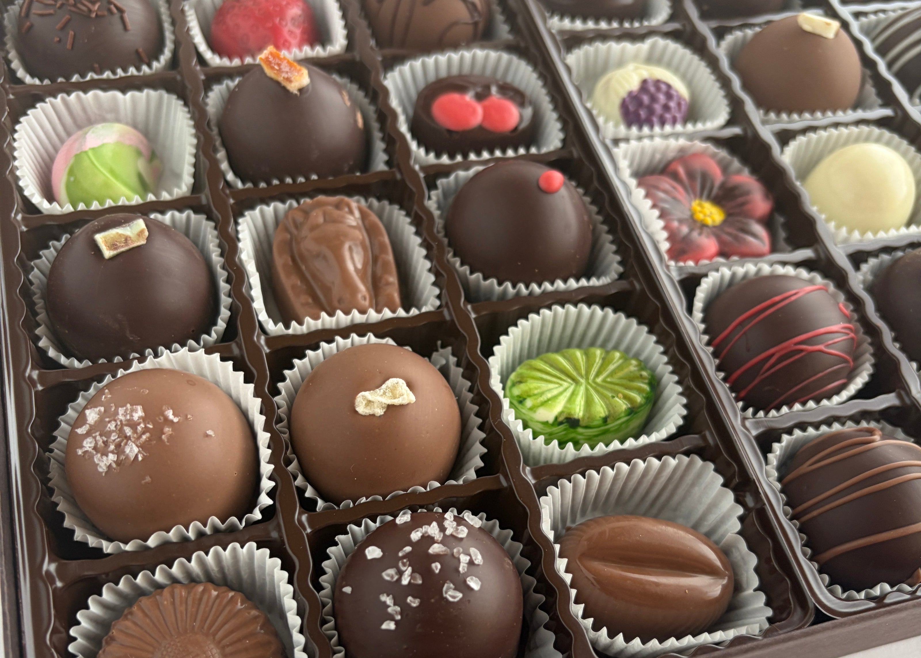 Assorted chocolate truffles in a box on a white background