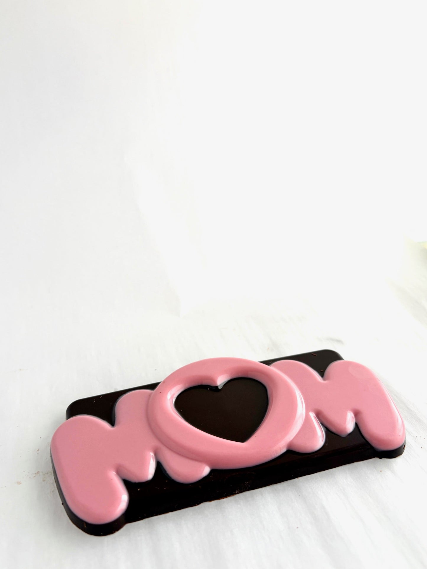 Chocolate bar with 'MOM' text and heart design on a white background