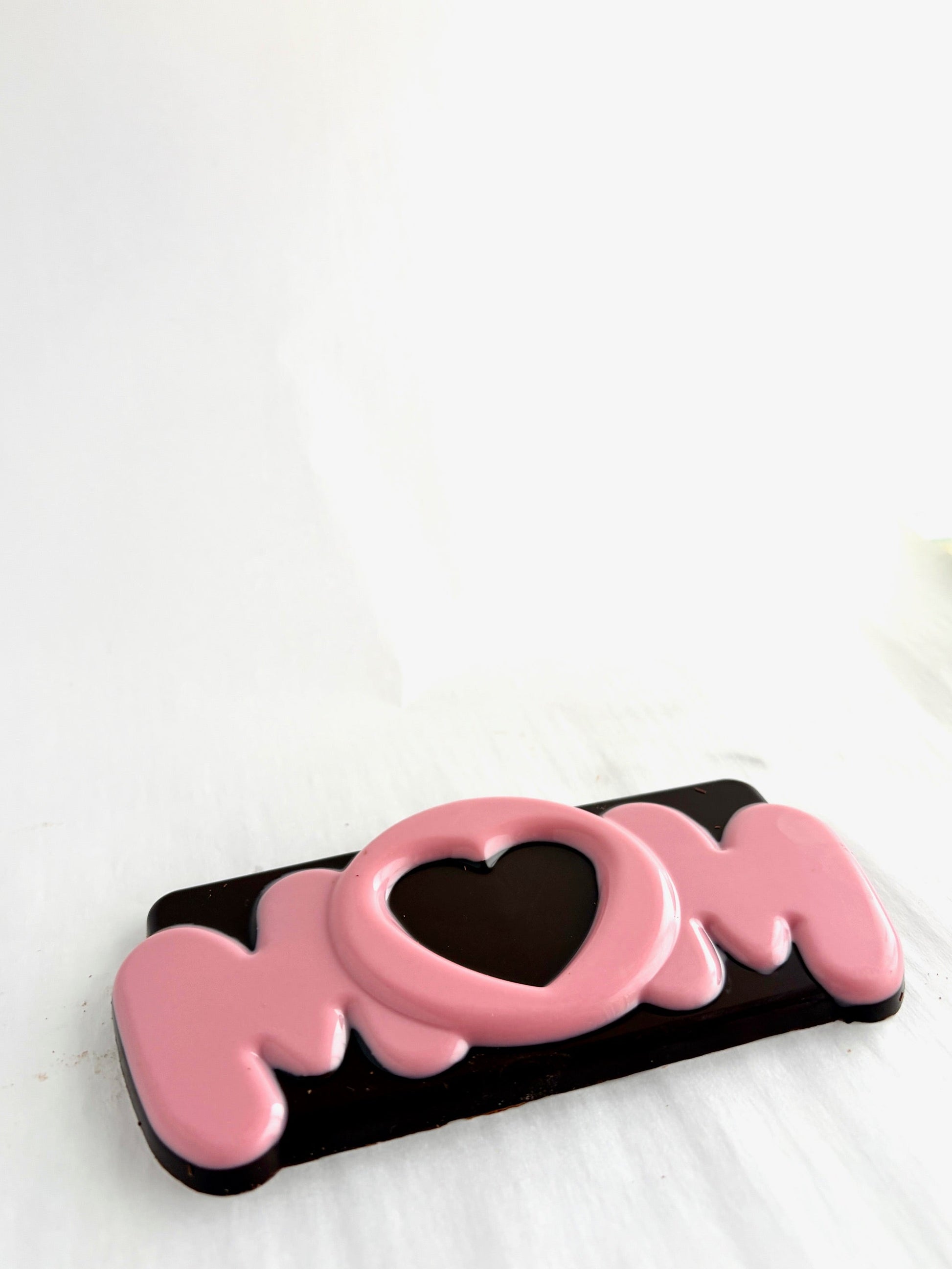 Chocolate bar with 'MOM' text and heart design on a white background